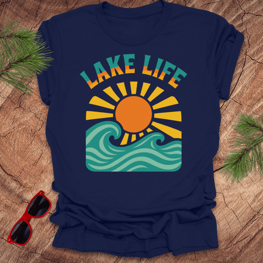 Navy blue t-shirt with a waves and sun graphic with text, 'Lake Life" on a wood background.
