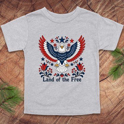 Gray t-shirt with an eagle design and 'Land of the Free' text on a wooden surface.