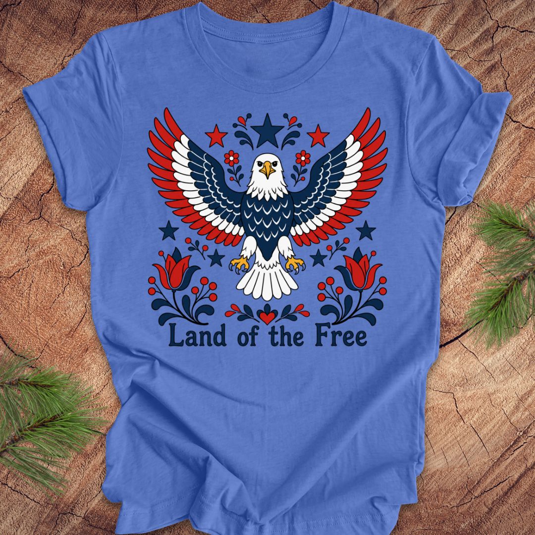 Blue t-shirt with an eagle design and 'Land of the Free' text on a wooden surface.