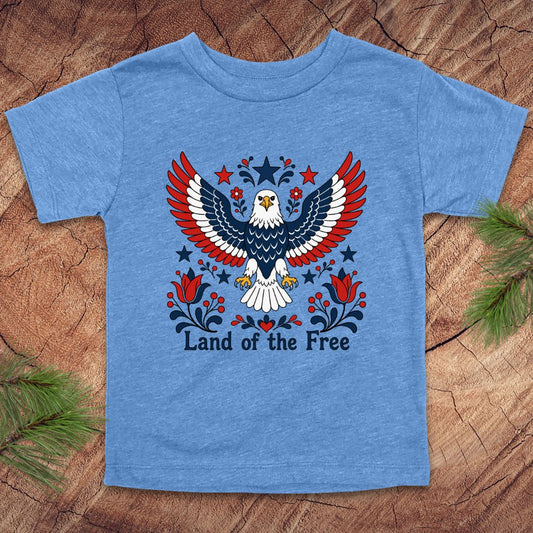 Blue t-shirt with an eagle design and 'Land of the Free' text on a wooden surface.