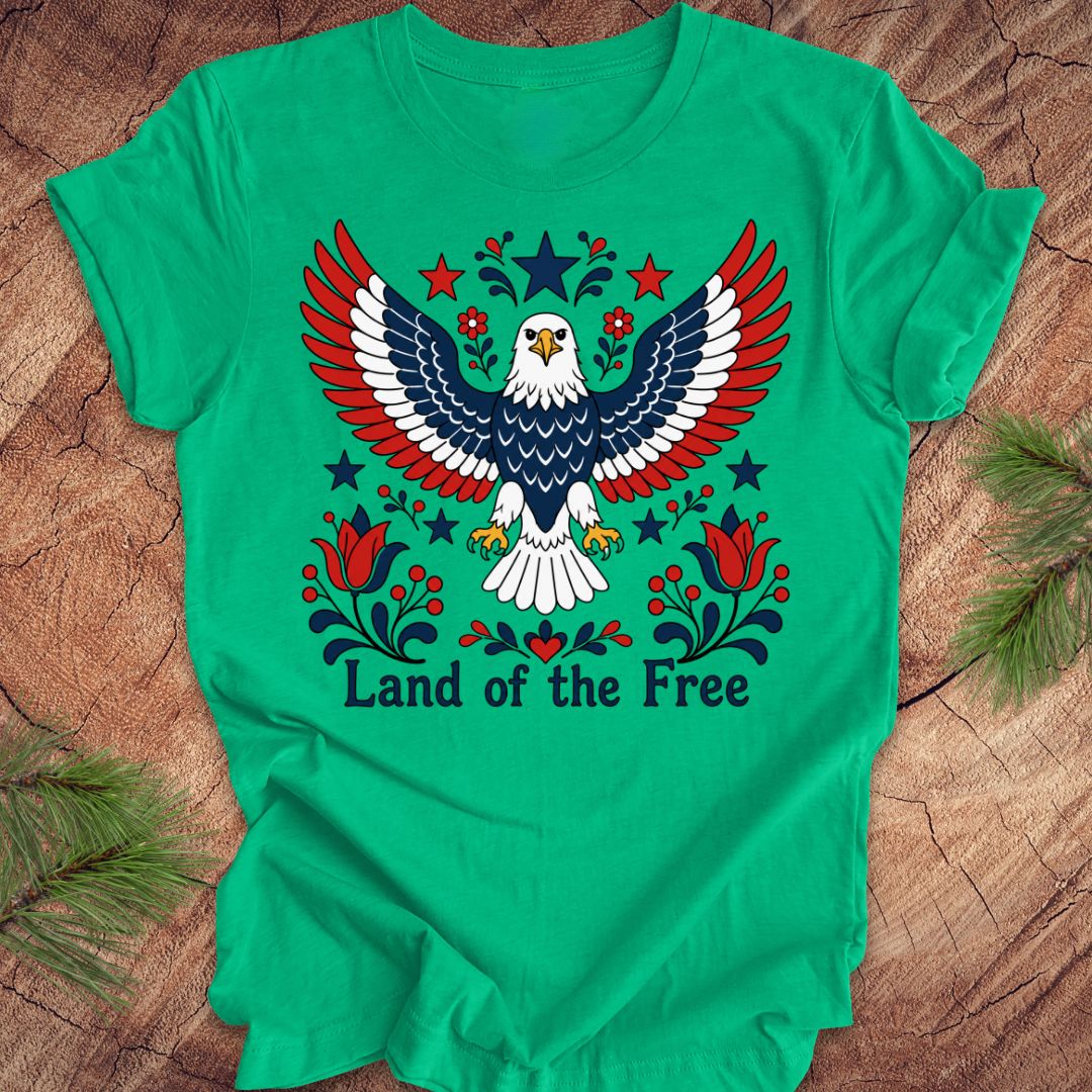 Green t-shirt with an eagle design and 'Land of the Free' text on a wooden surface.