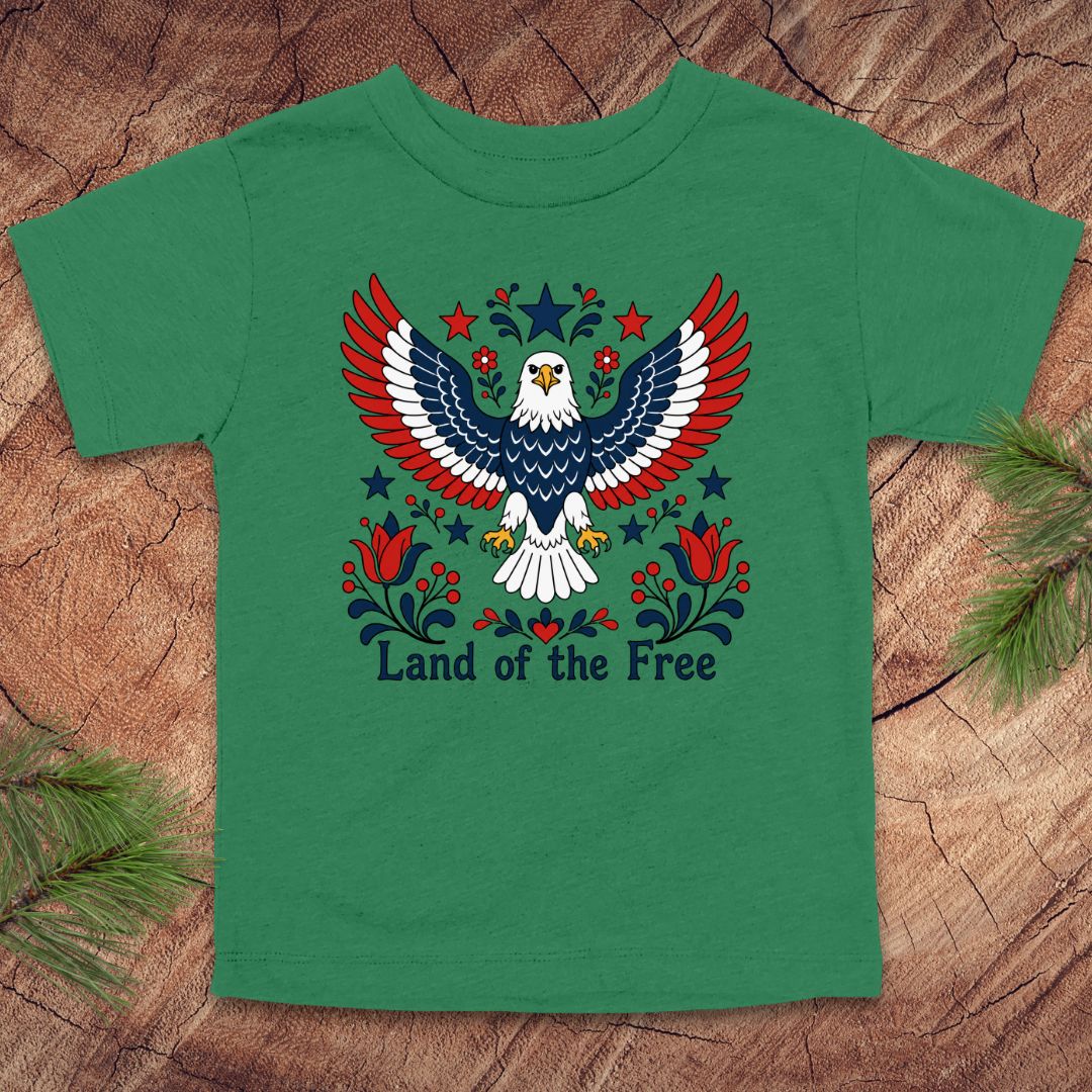 Green t-shirt with an eagle design and 'Land of the Free' text on a wooden surface.