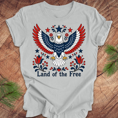 Gray t-shirt with an eagle design and 'Land of the Free' text on a wooden surface.