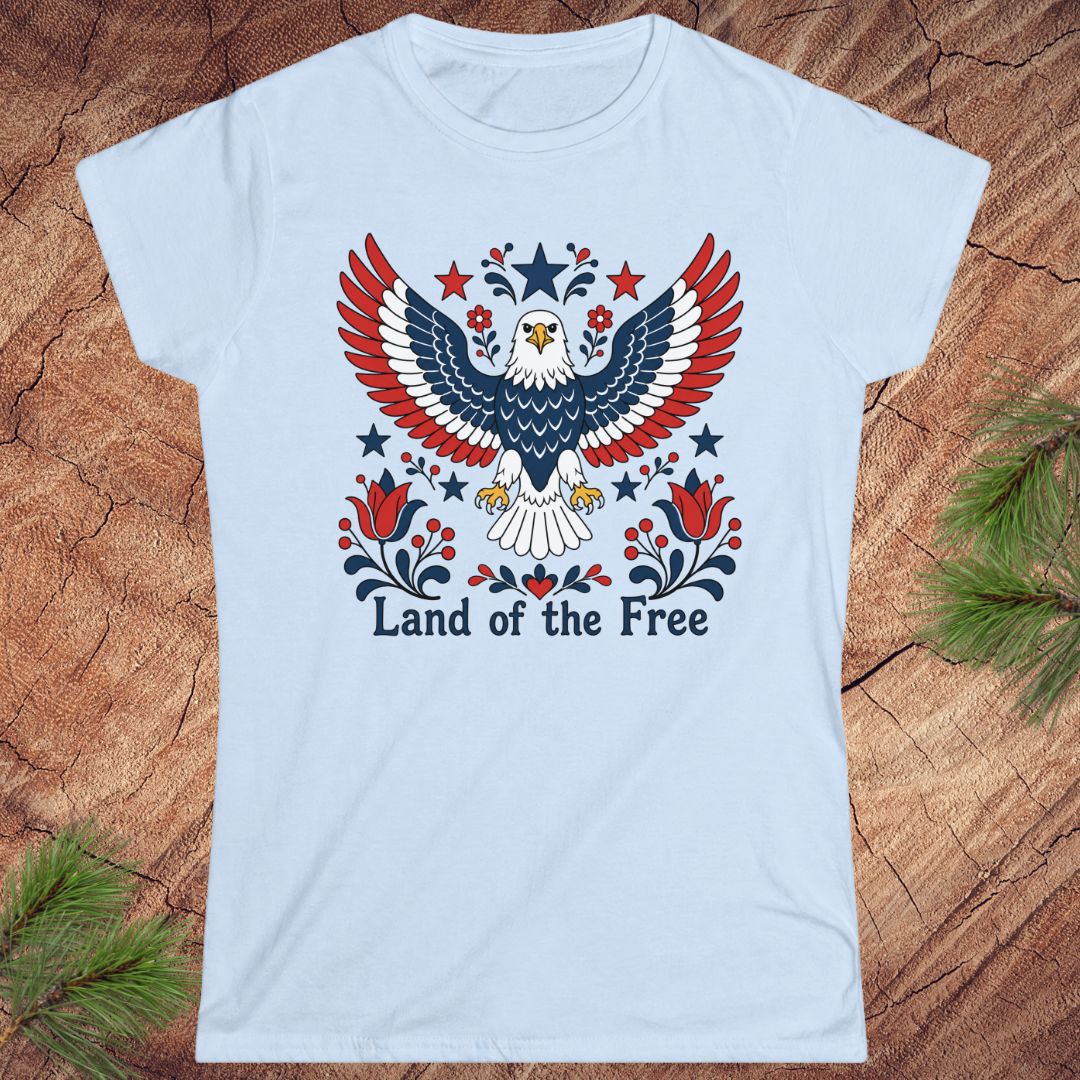 Light blue t-shirt with an eagle design and 'Land of the Free' text on a wooden surface.