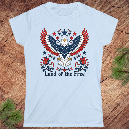 Light blue t-shirt with an eagle design and 'Land of the Free' text on a wooden surface.