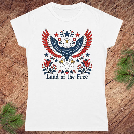 White t-shirt with an eagle design and 'Land of the Free' text on a wooden surface.