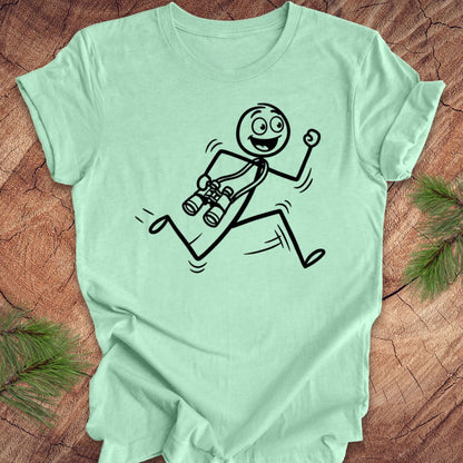 Mint green t-shirt with a stick figure design running with binoculars on a wooden surface