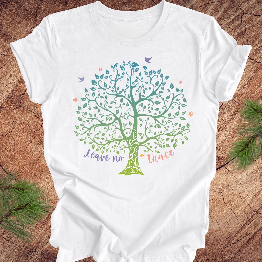 White t-shirt with a colorful tree design and text on a wooden surface.