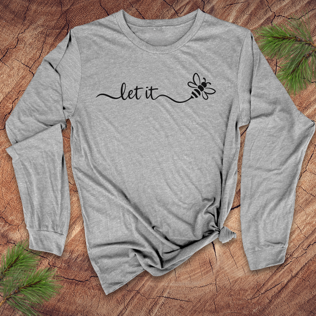 Gray long-sleeve shirt with 'let it' and bee design on a wooden surface