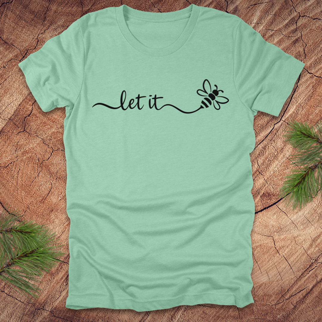 Mint green t-shirt with 'let it' and bee design on a wooden surface