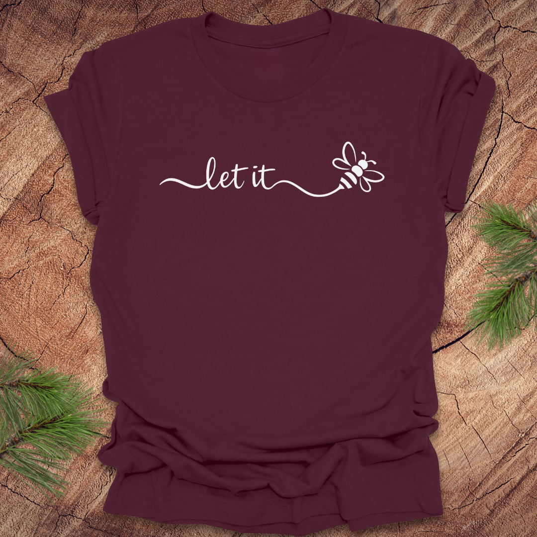Maroon t-shirt with 'let it' and bee design on a wooden surface