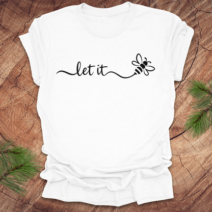 White t-shirt with 'let it' and bee design on a wooden surface