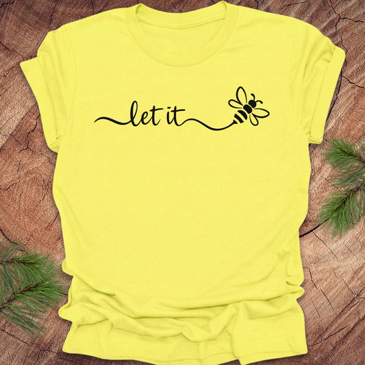 Yellow t-shirt with 'let it' and a bee design on a wooden surface