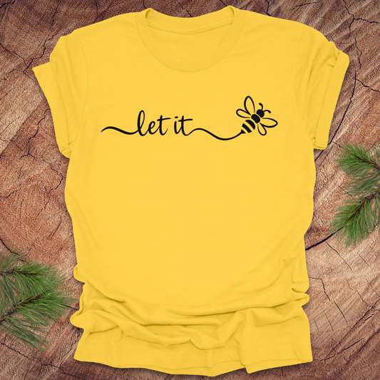Yellow t-shirt with 'let it' and a bee design on a wooden surface
