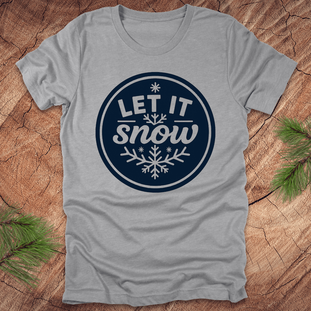 Gray t-shirt with 'Let It Snow' design on a wooden surface