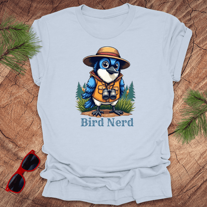 Light blue t-shirt with an animated blue jay in birdwatching gear with "bird nerd" text on a wood background.