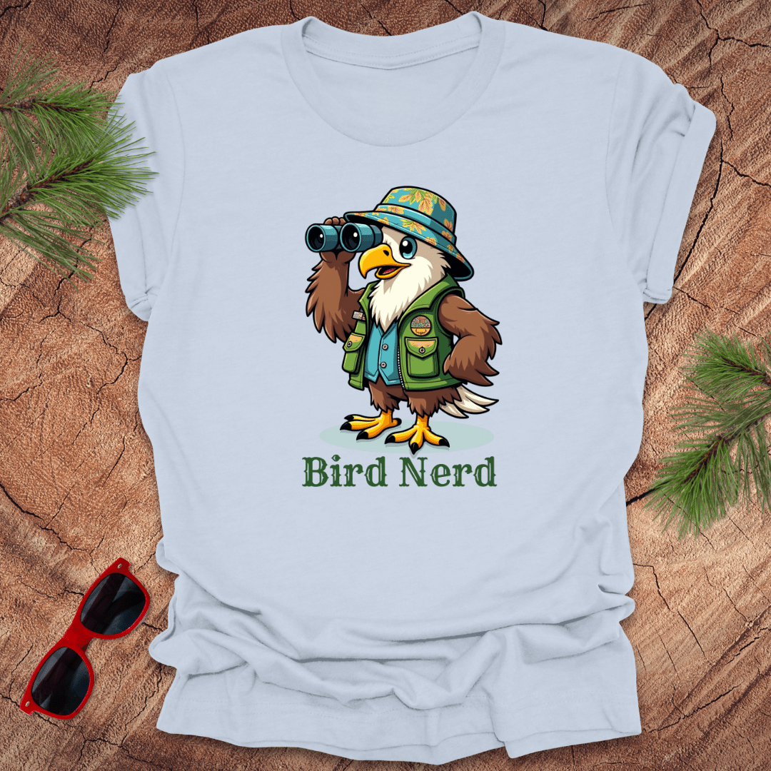 Light blue t-shirt with an animated eagle in birdwatching gear with "bird nerd" text on a wood background.