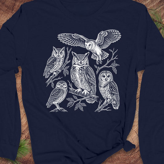 A navy blue long-sleeve t-shirt with a detailed white graphic print of five owls on the front, styled flat on a rustic wood background.