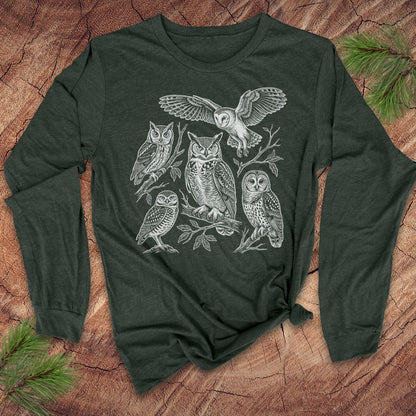 Green long-sleeve tshirt with white owl design on a wooden surface