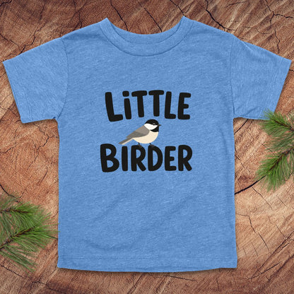 Blue t-shirt with 'Little Birder' text and a bird illustration on a wooden surface.