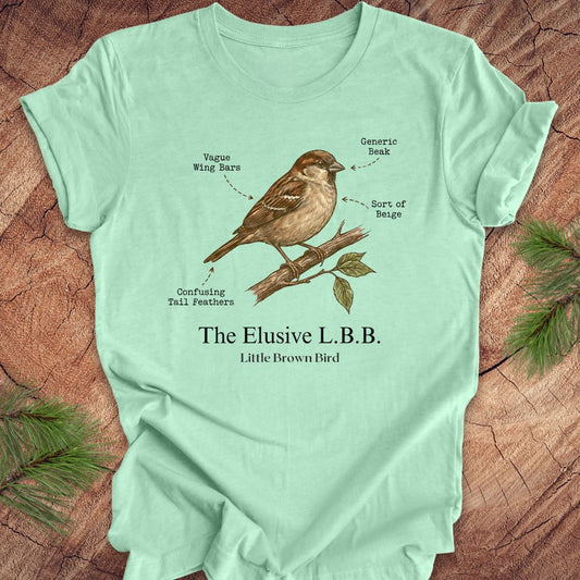 Light green t-shirt with a bird illustration and text on a wooden surface