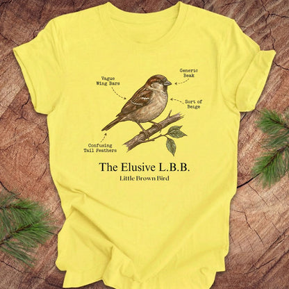 Yellow t-shirt with a bird illustration and text on a wooden surface