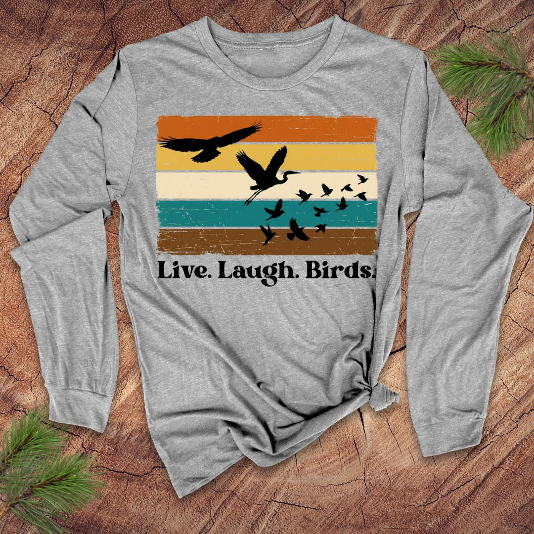 Gray long-sleeve shirt with bird design and 'Live. Laugh. Birds.' text on a wooden surface.