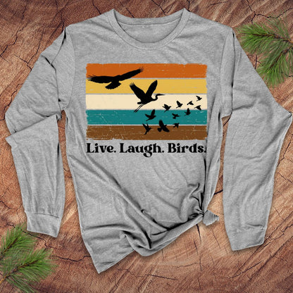 Gray long-sleeve shirt with bird design and 'Live. Laugh. Birds.' text on a wooden surface.