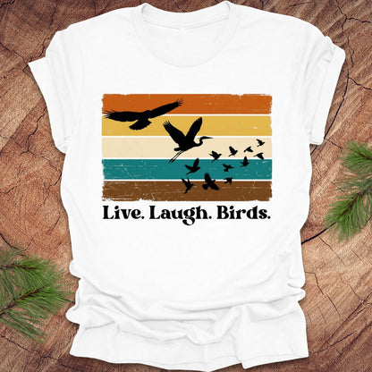White t-shirt with bird graphic and 'Live. Laugh. Birds.' text on a wooden surface.