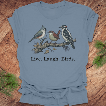 Blue t-shirt with bird illustration and 'Live. Laugh. Birds.' text on a wooden surface.