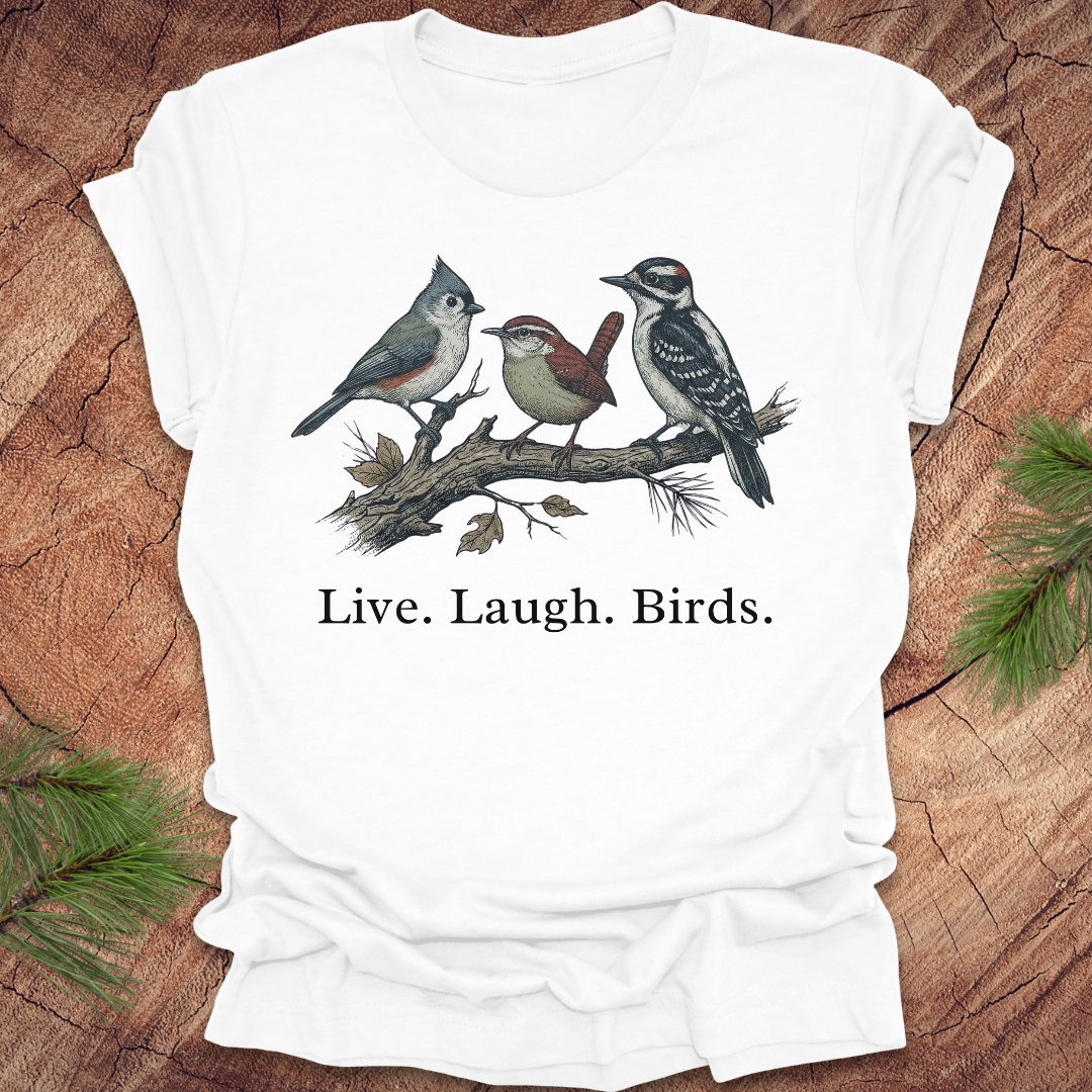White t-shirt with bird illustration and 'Live. Laugh. Birds.' text on a wooden surface.