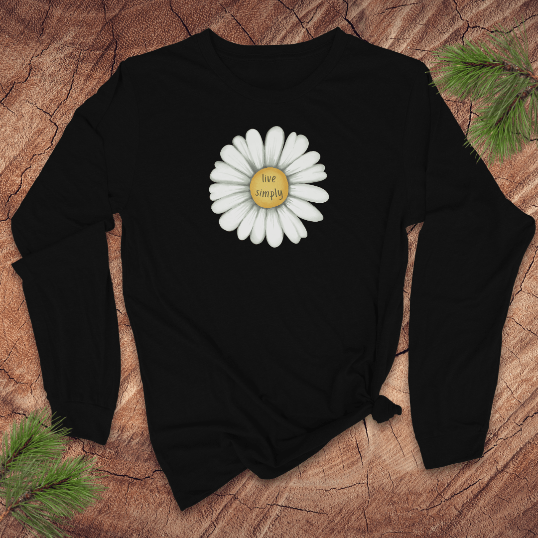 Black long-sleeve tshirt with a white daisy and 'live simply' text on a wooden surface