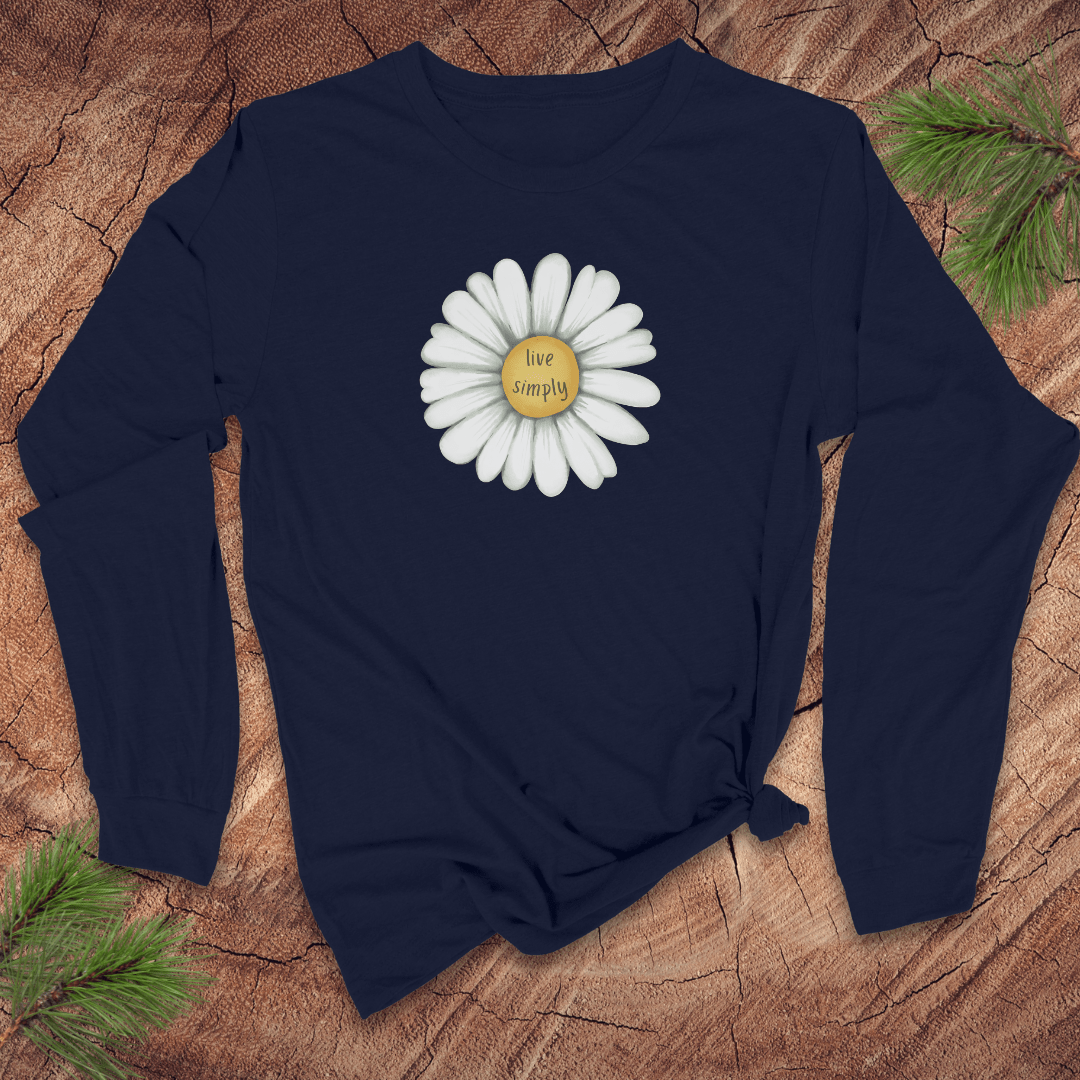 Navy blue long-sleeve shirt with a white daisy graphic and 'live simply' text on a wooden surface.