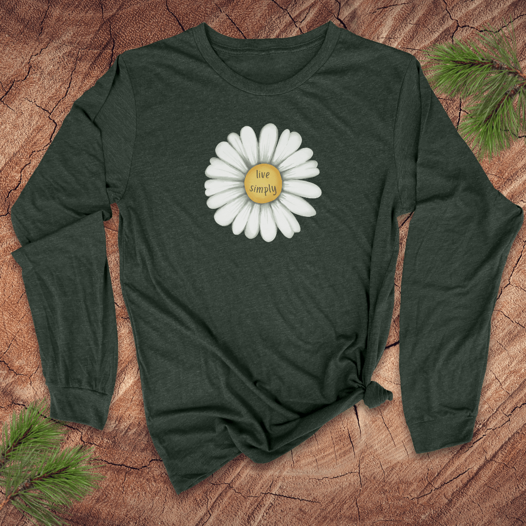 Green long-sleeve shirt with a white daisy graphic and 'live simply' text on a wooden surface.