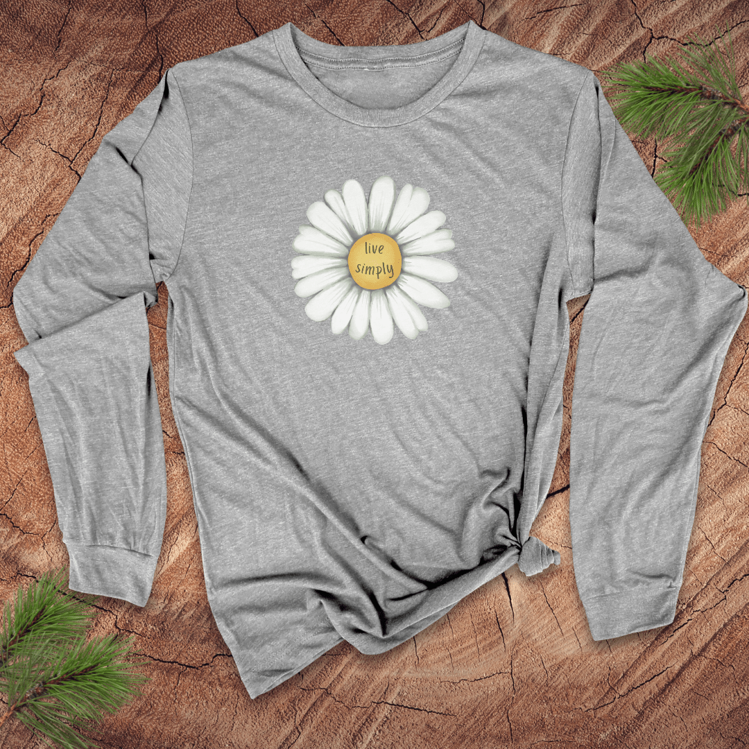 Gray long-sleeve shirt with a white daisy graphic and 'live simply' text on a wooden surface.