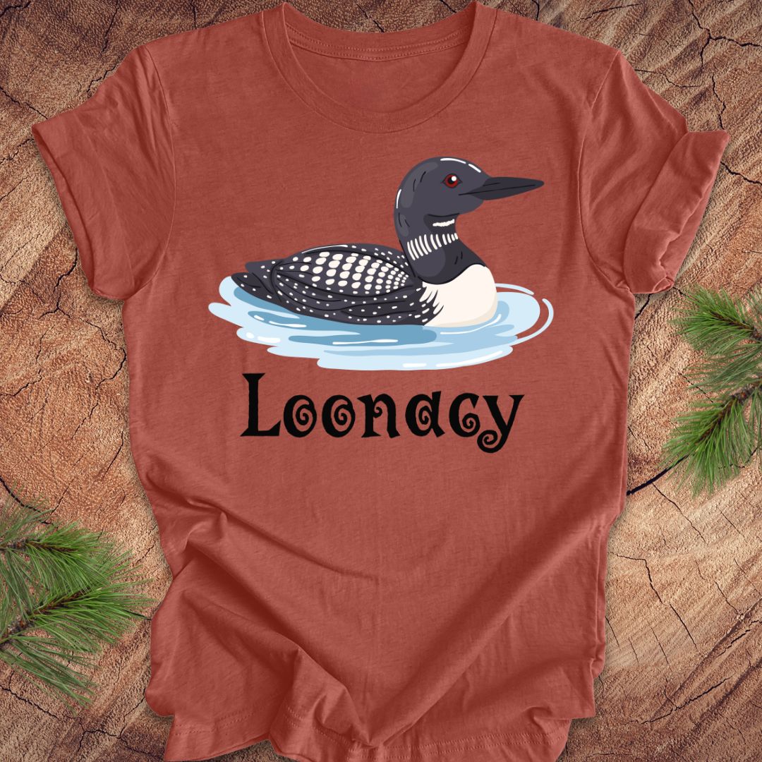 Clay colored t-shirt with a loon graphic and 'Loonacy' text on a wooden surface.