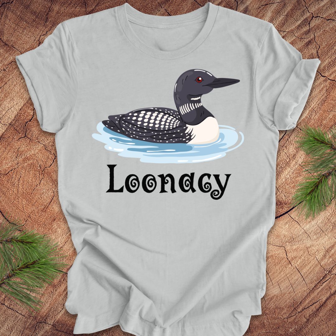 Gray t-shirt with a loon graphic and 'Loonacy' text on a wooden surface.