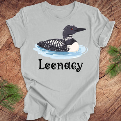 Gray t-shirt with a loon graphic and 'Loonacy' text on a wooden surface.