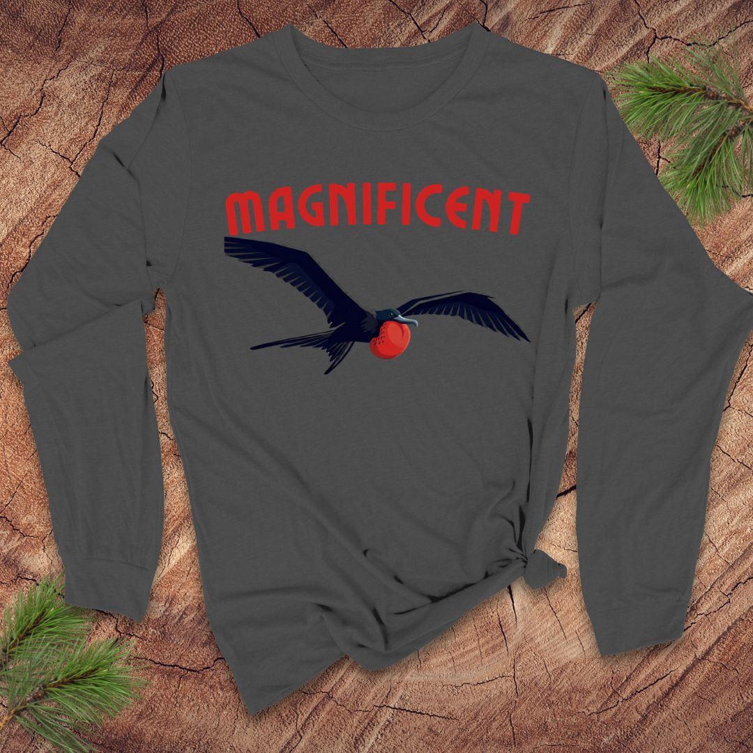 Gray long-sleeve shirt with a frigatebird graphic and 'MAGNIFICENT' text on a wooden surface.