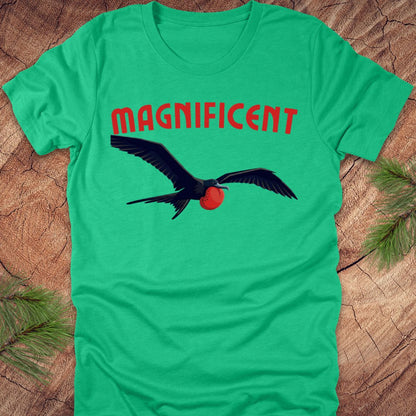 Green t-shirt with a bird graphic and 'MAGNIFICENT' text on a wooden surface.