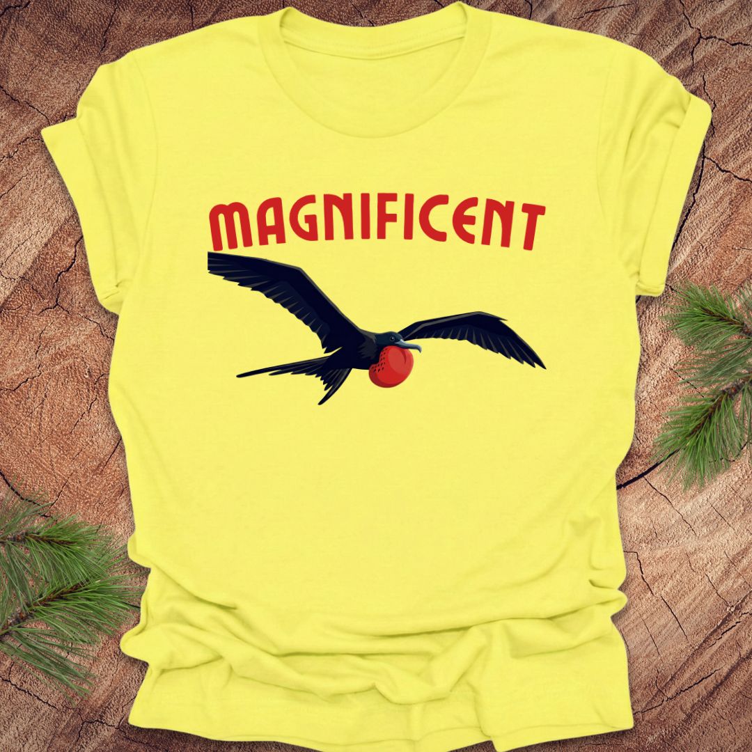 Yellow t-shirt with a bird graphic and 'MAGNIFICENT' text on a wooden surface.