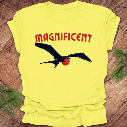Yellow t-shirt with a bird graphic and 'MAGNIFICENT' text on a wooden surface.