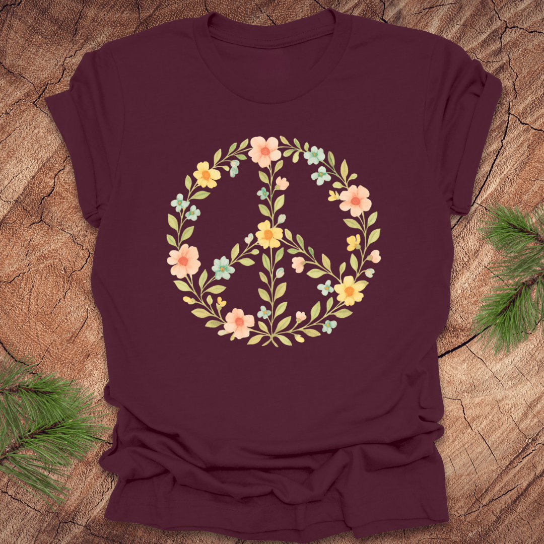 Maroon t-shirt with a peace sign made of flowers on a wood background.