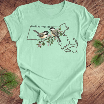 Mint green t-shirt with Massachusetts map and birds design on a wooden surface
