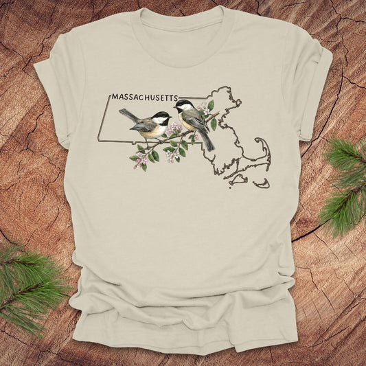 Beige t-shirt with Massachusetts map and chickadee design on a wooden surface