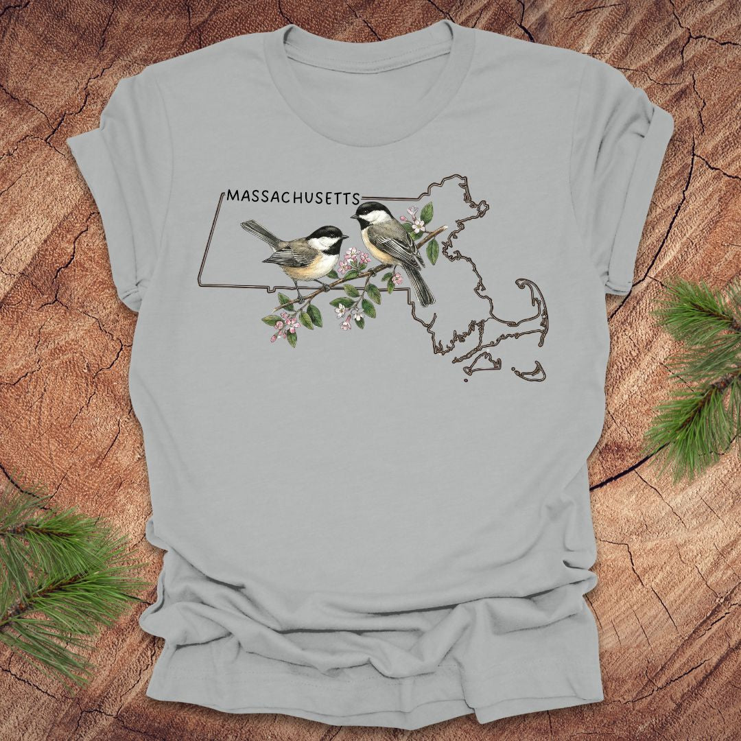 Silver t-shirt with Massachusetts map and chickadee design on a wooden surface