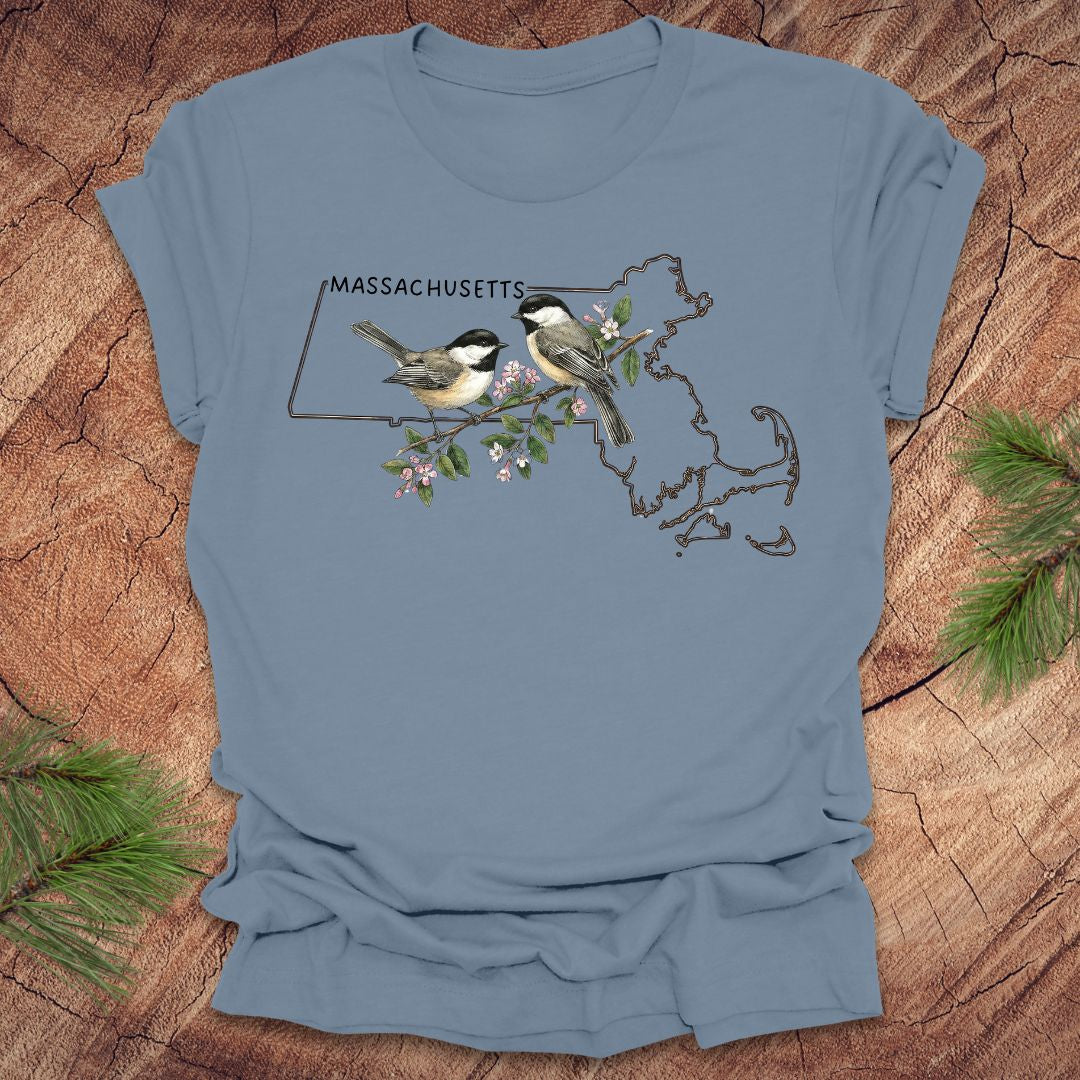 Steel blue t-shirt with Massachusetts map and chickadee design on a wooden surface