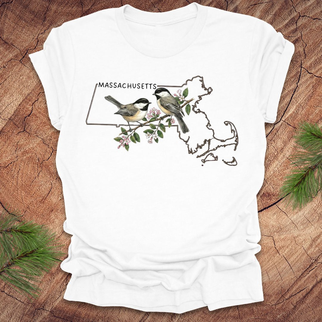 White t-shirt with Massachusetts map and chickadee design on a wooden surface