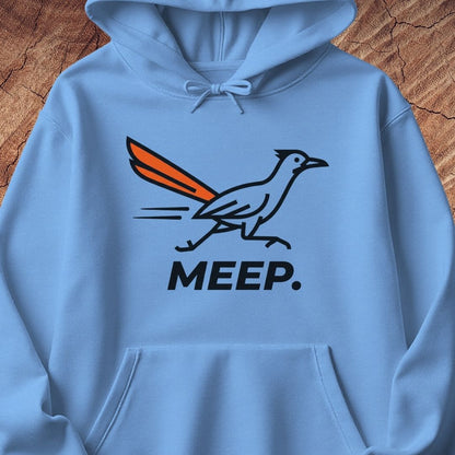 A light blue pullover hoodie featuring a graphic of a roadrunner with an orange tail and the word 'MEEP.' printed below in black, displayed against a rustic wood background.