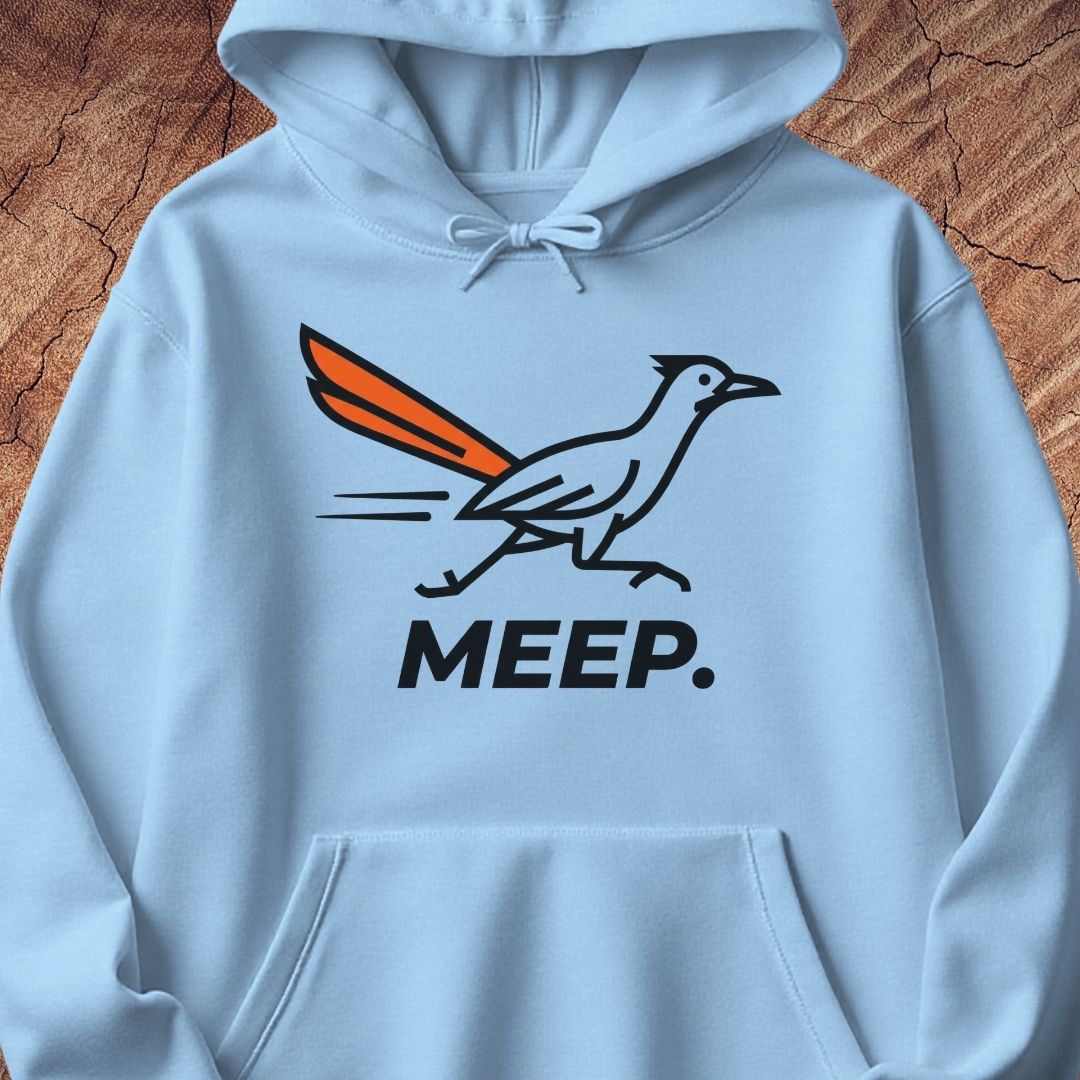 A light blue pullover hoodie featuring a graphic of a roadrunner with an orange tail and the word 'MEEP.' printed below in black, displayed against a rustic wood background.